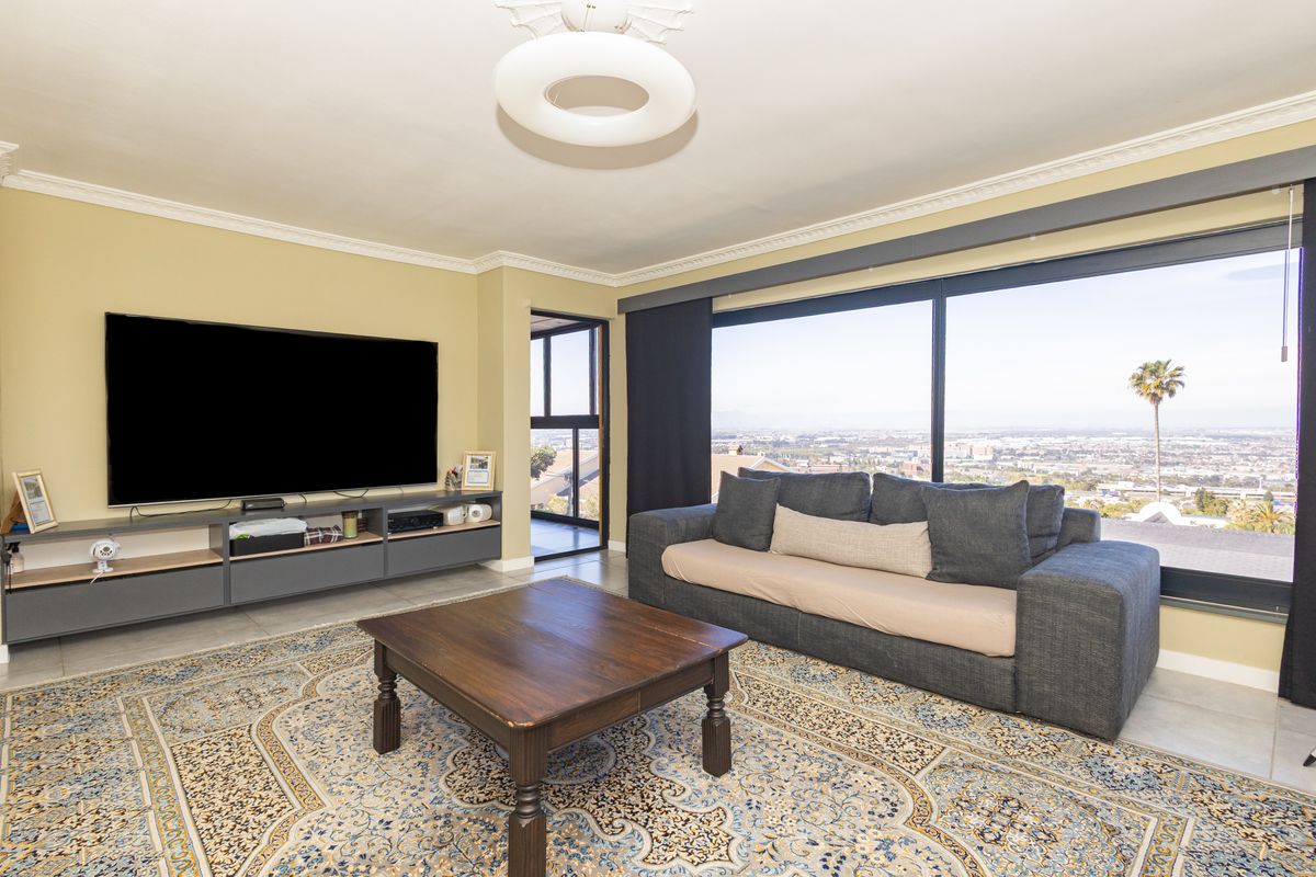 Spacious living room featuring large sliding glass doors with panoramic views, crown molding, and a built-in media console.