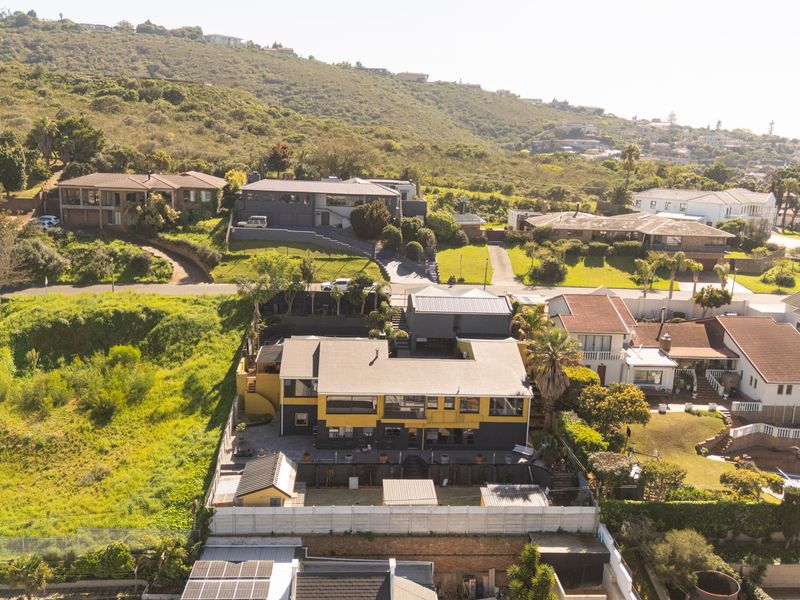 Aerial view of the property showing the building structure, roof profile, surrounding garden, and neighborhood context.