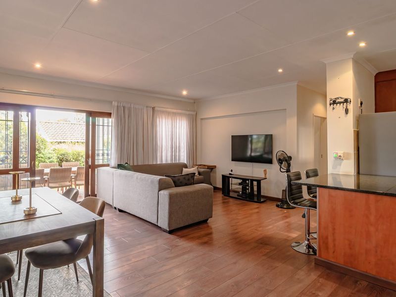 Spacious open-plan living and dining area featuring laminate flooring, recessed lighting, and a functional kitchen with granite countertops and a breakfast bar.