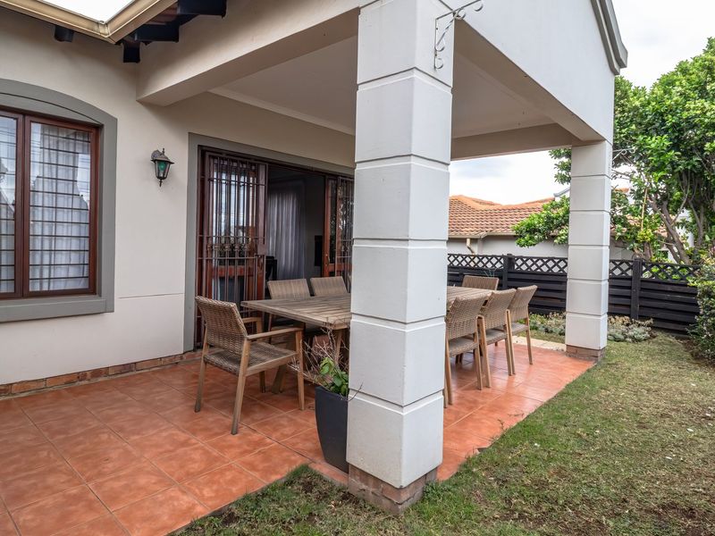 A covered outdoor patio featuring tiled flooring, structural columns, and direct access to the interior through timber-framed sliding doors.