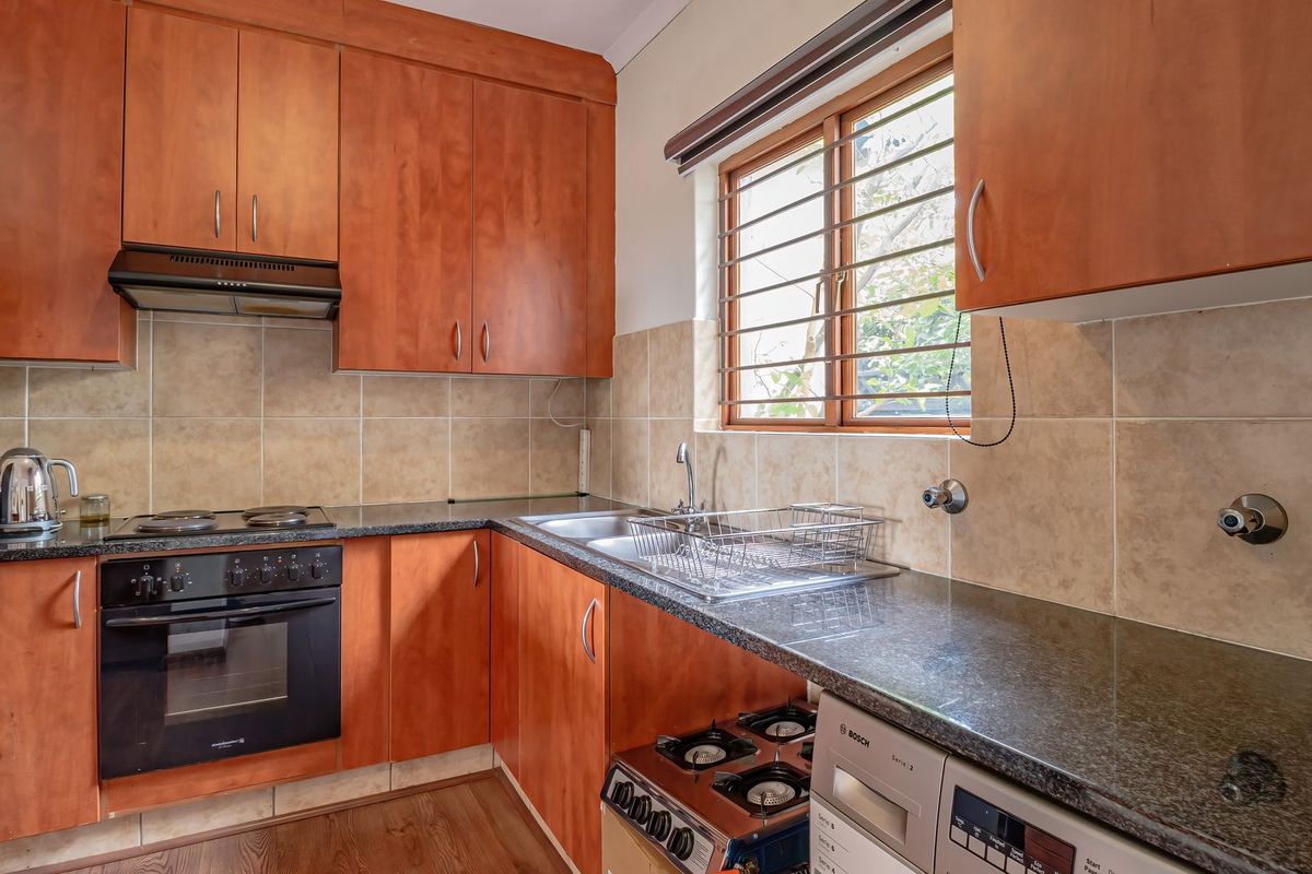A functional kitchen featuring wood-finish cabinetry, granite countertops, a built-in oven with hob, and a tiled backsplash.