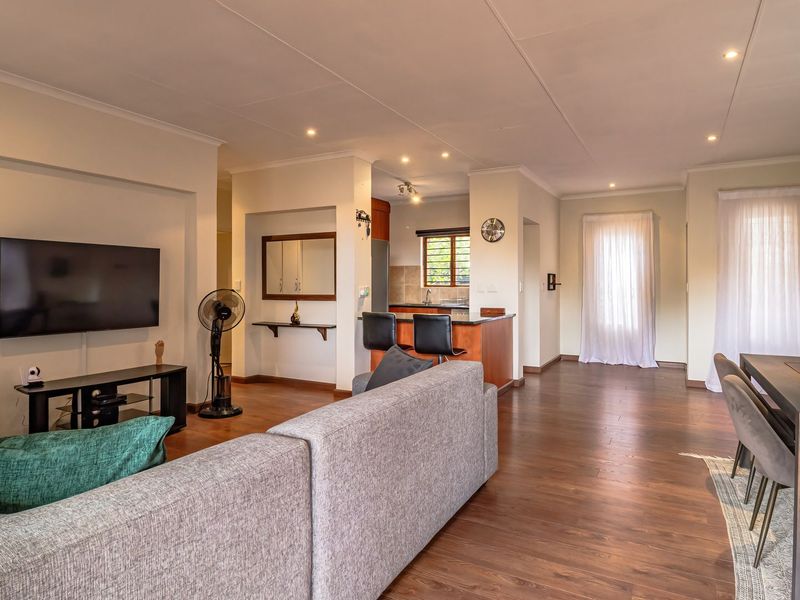 Spacious open-plan living and dining area featuring laminate flooring, recessed lighting, and a functional kitchen with a breakfast bar.