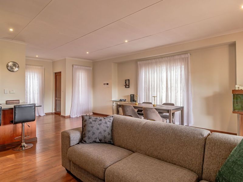 Spacious open-plan living and dining area featuring warm hardwood flooring, recessed lighting, and a functional kitchen with a breakfast bar.