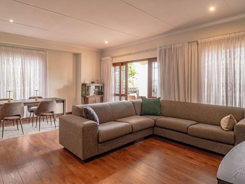 Spacious open-plan living and dining area featuring warm laminate flooring, recessed lighting, and large sliding glass doors providing access to the outdoor space.