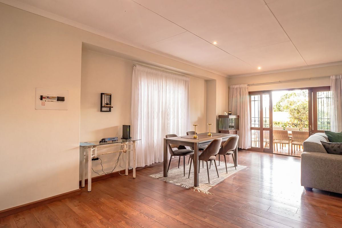 Spacious living and dining area featuring warm laminate flooring, recessed lighting, and large sliding glass doors providing access to the outdoor patio.