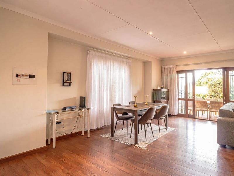 Spacious living and dining area featuring warm laminate flooring, recessed lighting, and large sliding glass doors providing access to the outdoor patio.