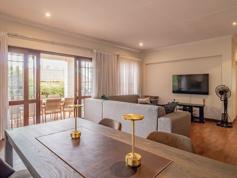 Spacious open-plan living and dining area featuring timber flooring, recessed lighting, and large sliding doors providing seamless access to the outdoor patio.