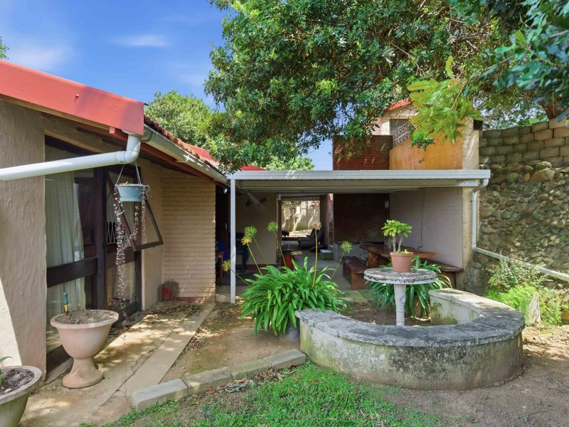 A covered outdoor patio area featuring a brick retaining wall, concrete planter, and direct access to the home's exterior.