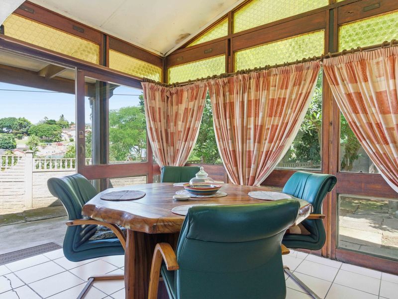 Enclosed patio area featuring timber-framed glazing, tiled flooring, and sliding door access to the exterior.