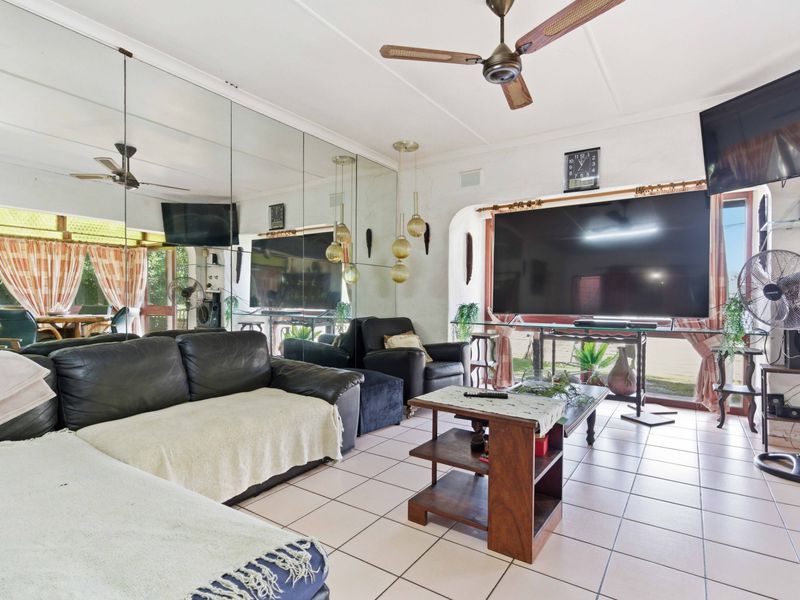 Living room featuring tiled flooring, a ceiling fan, and a large mirrored wall feature, offering potential for a modern update.