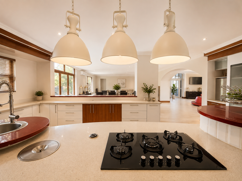 Spacious open-plan kitchen featuring a large island with gas cooktop, stone countertops, and modern pendant lighting, flowing into the adjacent living areas.