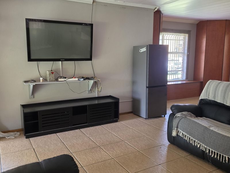 A living room featuring tiled flooring, a decorative ceiling light, and built-in cabinetry, offering a functional space with potential for cosmetic updates.