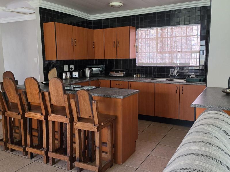 A functional kitchen featuring wood-look cabinetry, granite countertops, a breakfast bar, and tiled flooring, offering a practical layout for daily use.