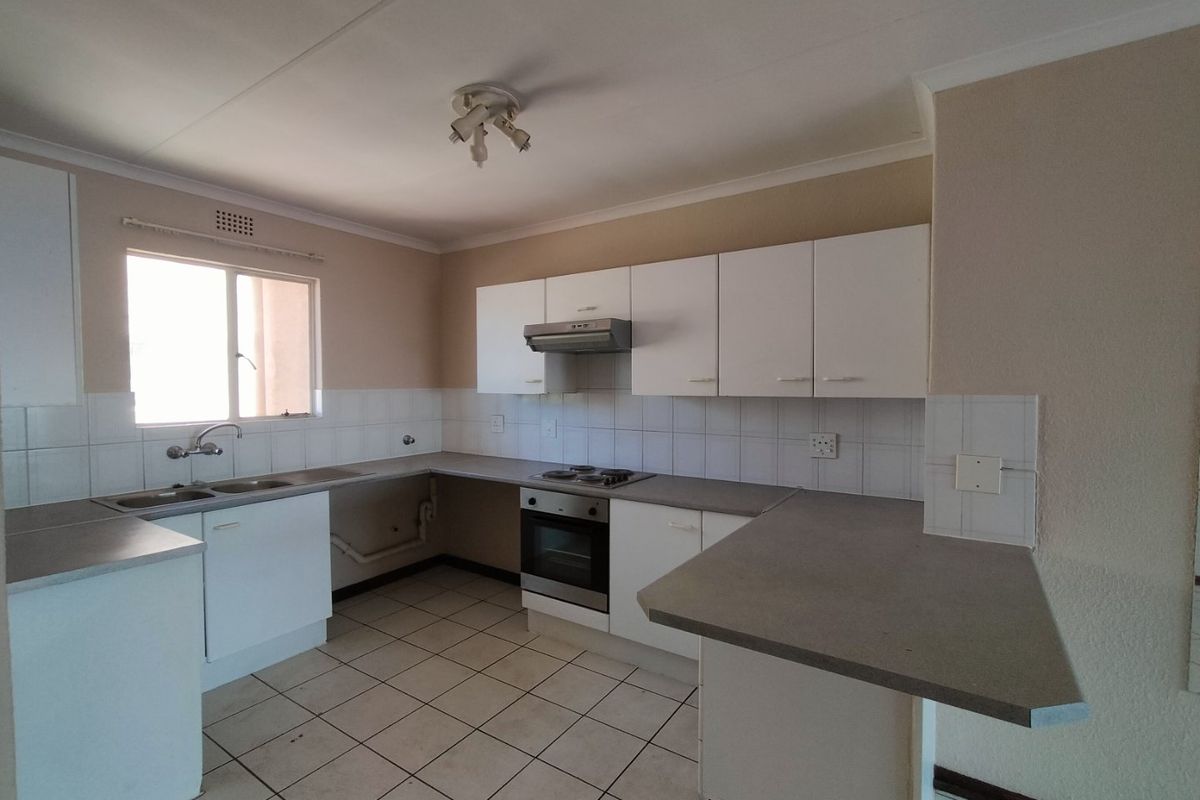 A functional kitchen featuring white cabinetry, laminate countertops, built-in oven, electric hob, and tiled flooring, offering a clean and practical workspace.