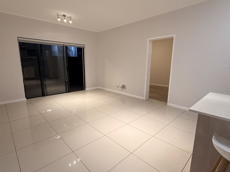 Spacious open-plan living area featuring large format floor tiles, modern recessed lighting, and a functional kitchen island with stone countertops.