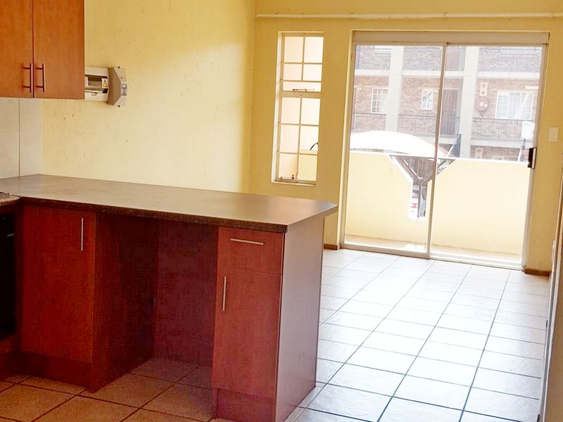 Open plan kitchen area featuring laminate cabinetry, tiled flooring, and a sliding glass door providing access to an outdoor balcony.
