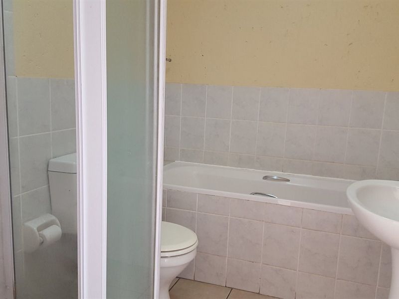 A functional bathroom featuring a built-in bathtub, pedestal basin, toilet, and a separate shower enclosure with tiled finishes.