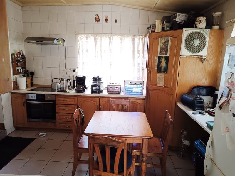 A dated kitchen featuring wooden cabinetry, tiled splashbacks, and built-in cooking appliances, offering potential for a modern renovation.