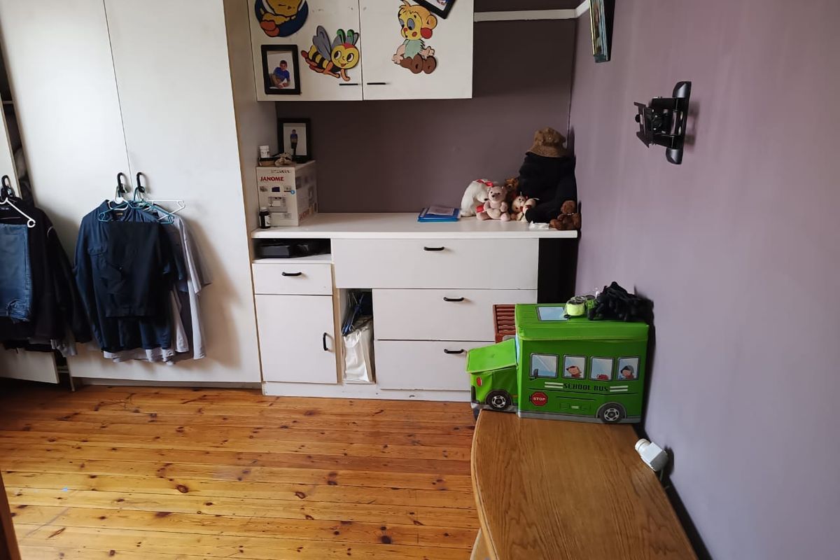 Bedroom featuring timber flooring, built-in cupboards with overhead storage, and a wall-mounted television bracket.