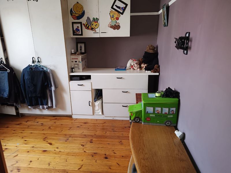 Bedroom featuring timber flooring, built-in cupboards with overhead storage, and a wall-mounted television bracket.