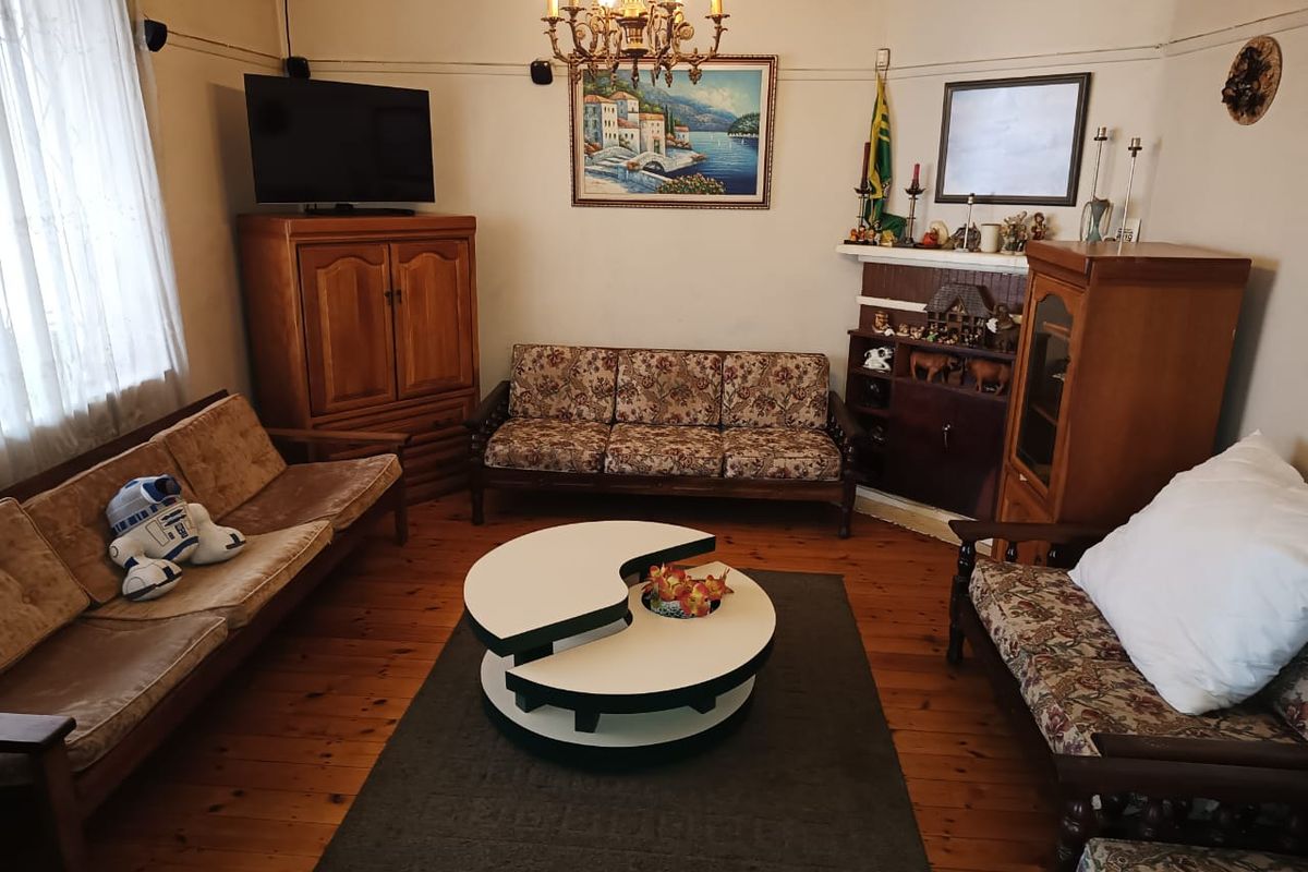 A traditional living room featuring polished timber flooring, a central chandelier, and a built-in fireplace mantle.