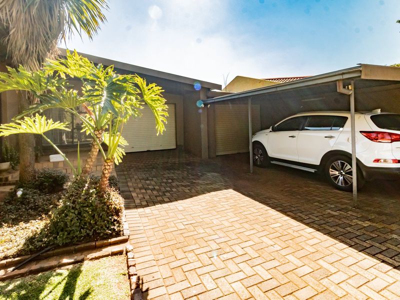 Front exterior view featuring a paved driveway, a covered carport, and a garage entrance.