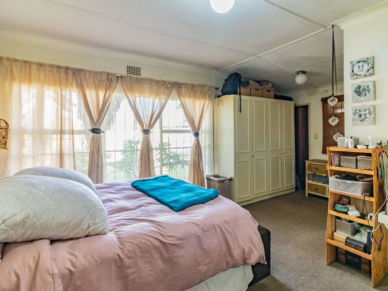 A bedroom featuring built-in wardrobes, carpet flooring, and security bars on the windows. The room requires cosmetic updates to the ceiling and finishes.