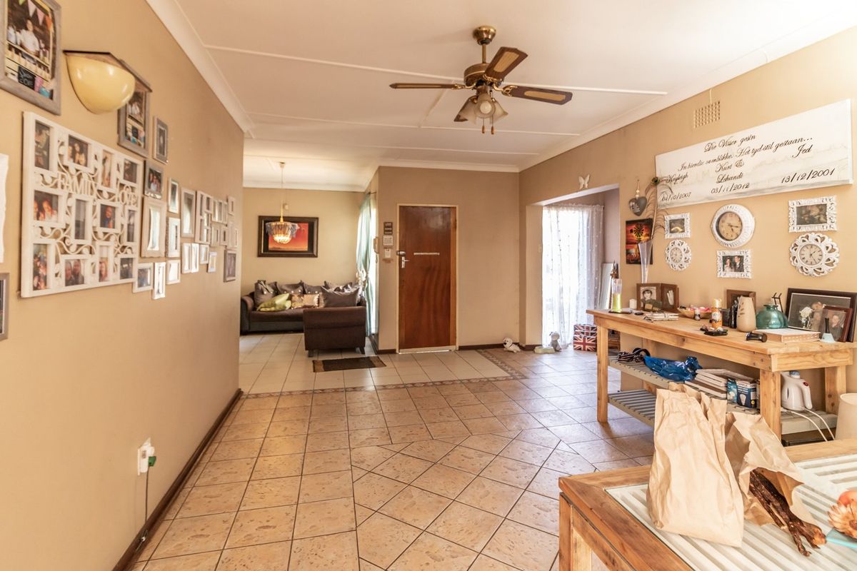 A spacious living area featuring tiled flooring, a ceiling fan, and coved ceilings, providing a neutral base for potential interior updates.