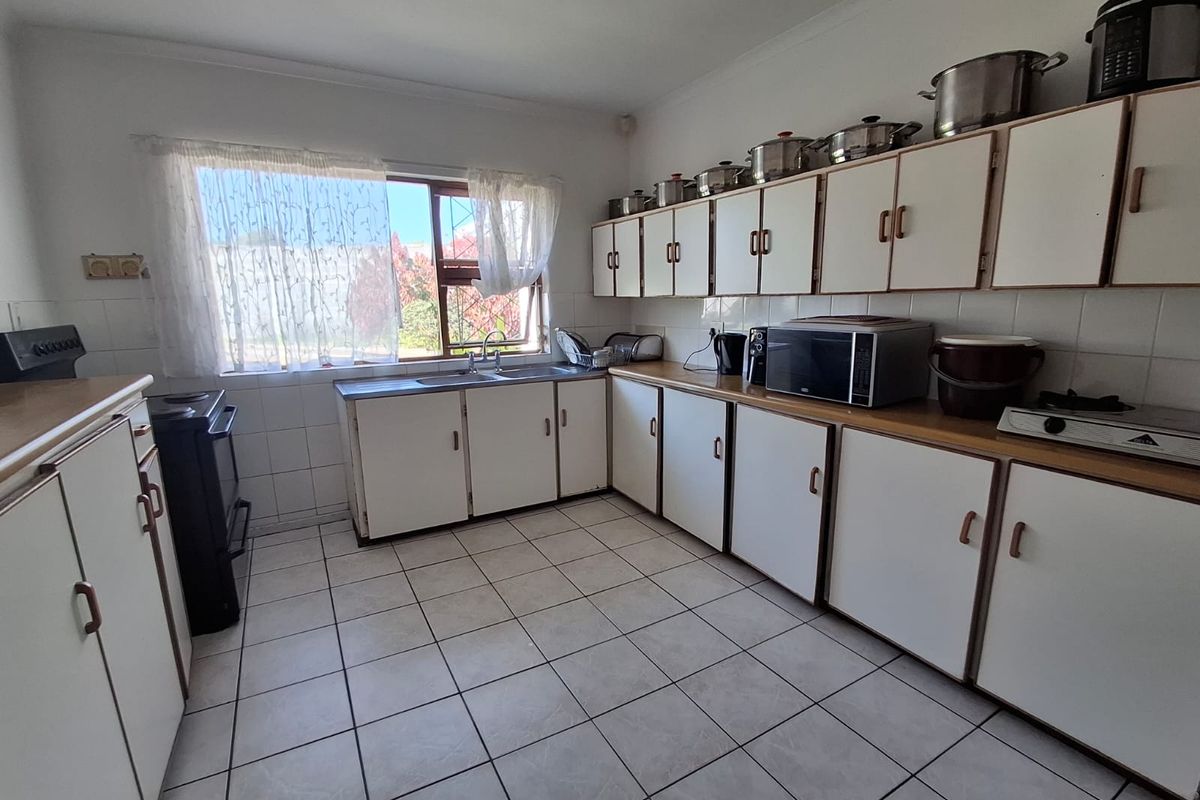 A functional kitchen featuring white built-in cabinetry, laminate countertops, tiled flooring, and a double basin sink with a window view.