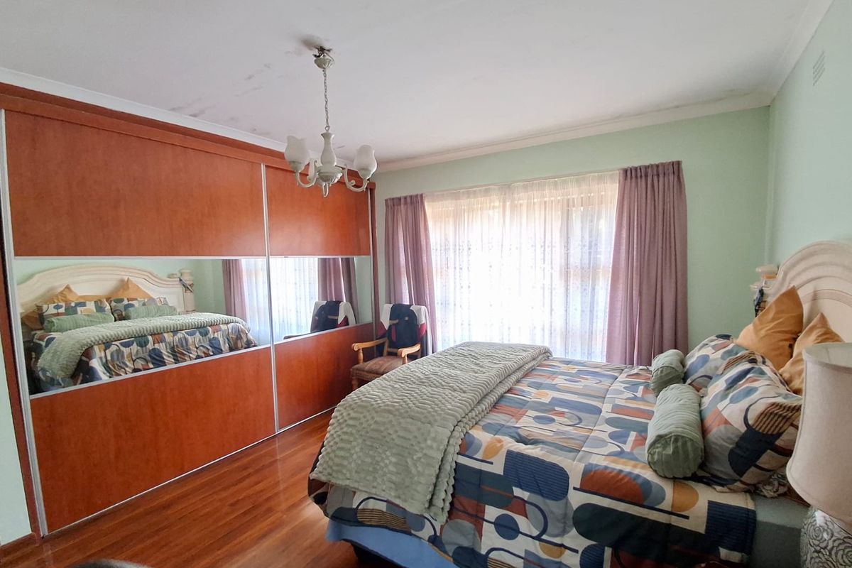 A bedroom featuring hardwood flooring, a large built-in wardrobe with mirrored panels, and decorative ceiling coving.