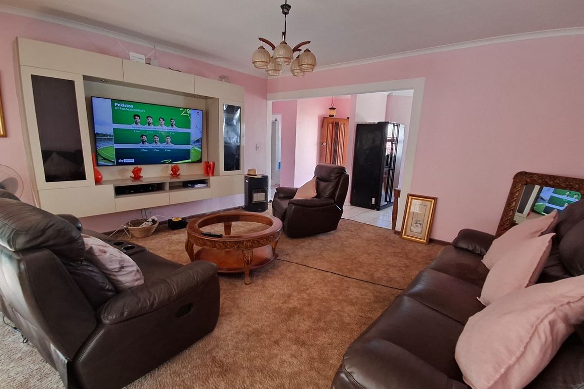 A living room featuring a built-in media unit, carpeted flooring, and a central ceiling light fixture, providing a functional and comfortable living space.