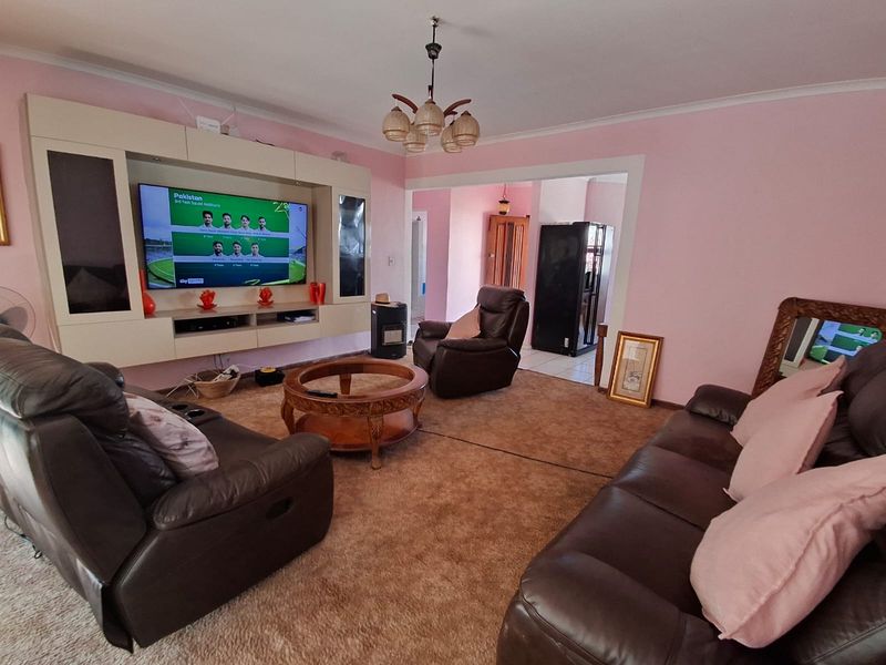 A living room featuring a built-in media unit, carpeted flooring, and a central ceiling light fixture, providing a functional and comfortable living space.