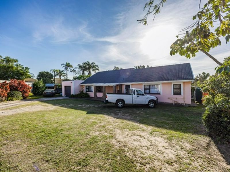 Front view of a single-story residential house featuring a tiled roof, attached garage, and a spacious front lawn with a driveway.