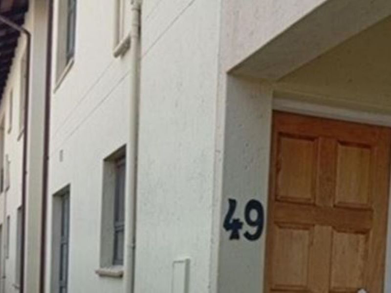 Exterior view of the apartment entrance featuring a timber front door and covered entryway.
