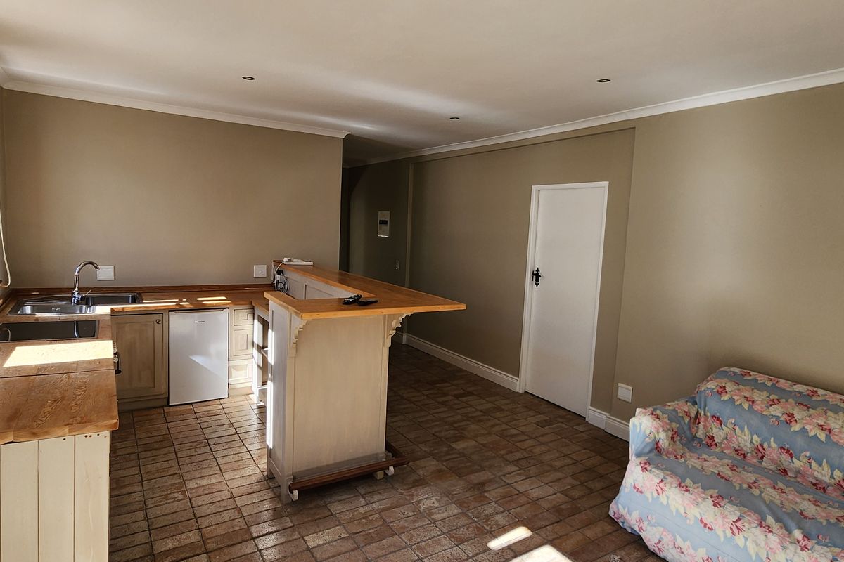 Open-plan living area featuring a functional kitchen with wooden countertops, a breakfast bar, and tiled flooring throughout.