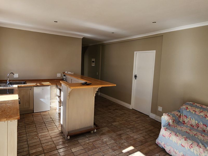 Open-plan living area featuring a functional kitchen with wooden countertops, a breakfast bar, and tiled flooring throughout.