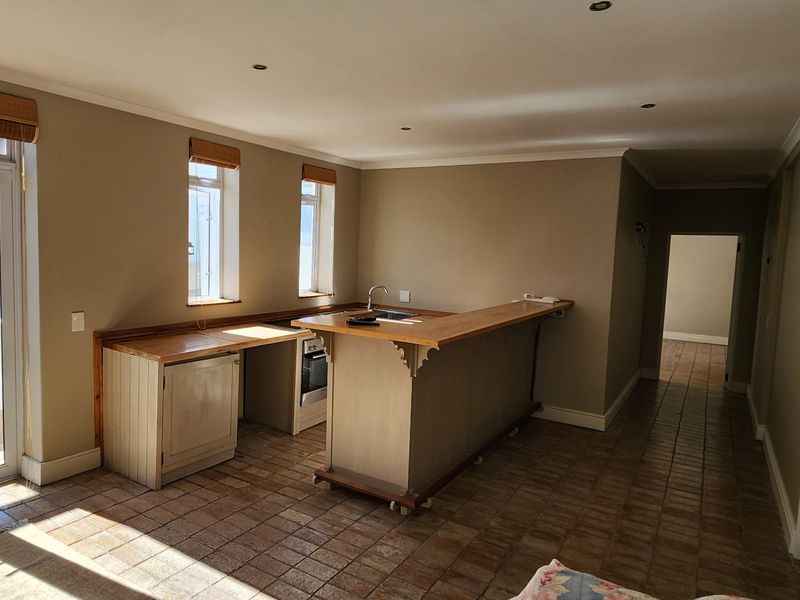 Open plan living and kitchen area featuring tiled flooring, built-in cabinetry with wooden countertops, and direct access to an outdoor patio through french doors.