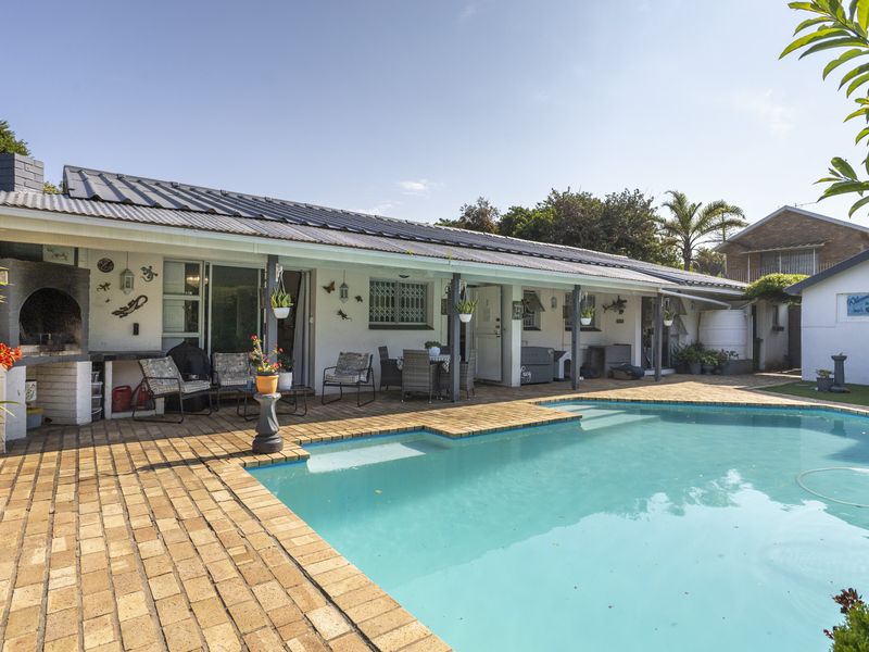 Outdoor entertainment area featuring a swimming pool, brick-paved patio, and a covered veranda with a built-in braai.