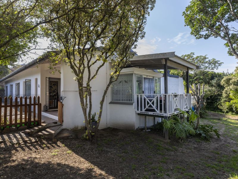 Rear view of the house featuring a covered patio with timber balustrade, security gates, and a surrounding garden area.