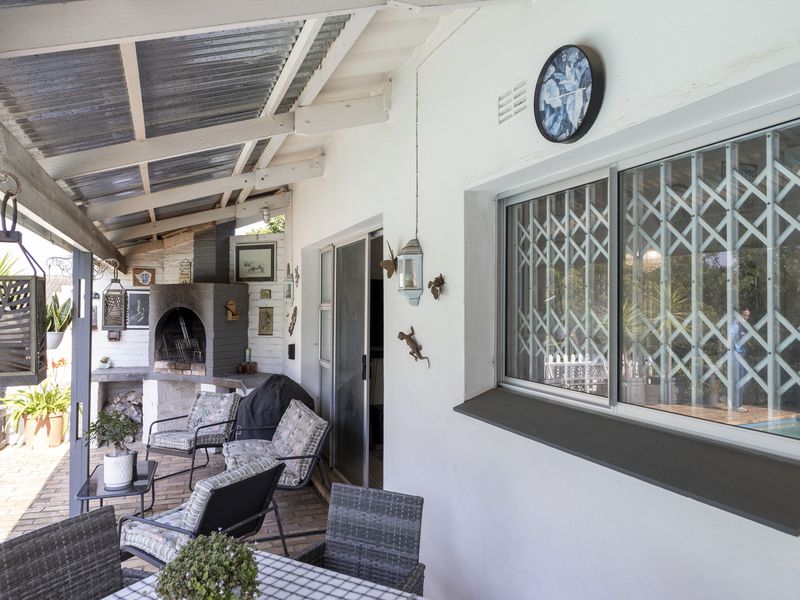 Covered patio area featuring a built-in braai, brick paving, and sliding door access to the main house.
