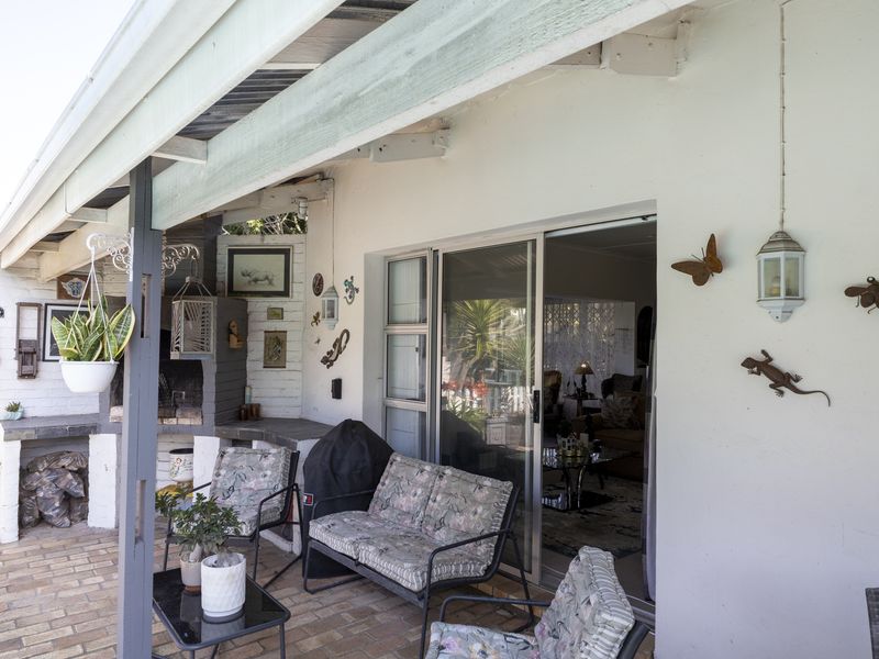 Covered patio area featuring brick paving and a built-in braai, providing direct access to the interior living space through sliding glass doors.