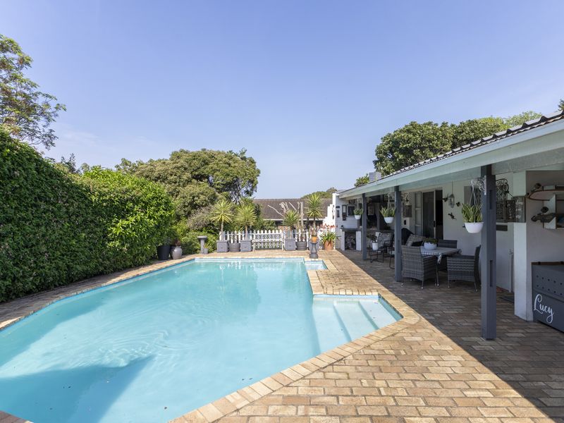 A well-maintained outdoor pool area featuring a brick-paved patio and a covered veranda, perfect for relaxation and outdoor entertaining.