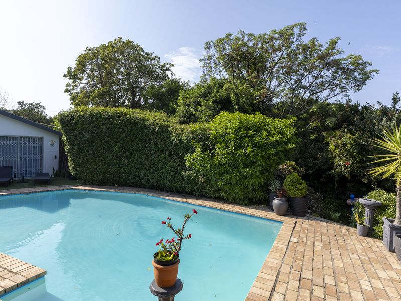 A well-maintained outdoor pool area featuring brick paving and established garden landscaping, providing a private and inviting space for relaxation.