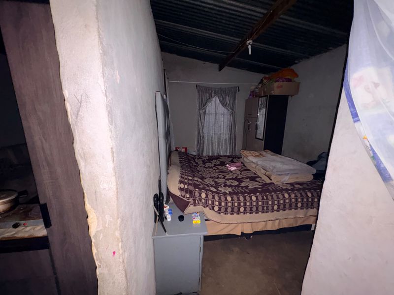 A bedroom featuring exposed timber rafters and a corrugated metal ceiling with unfinished wall surfaces.
