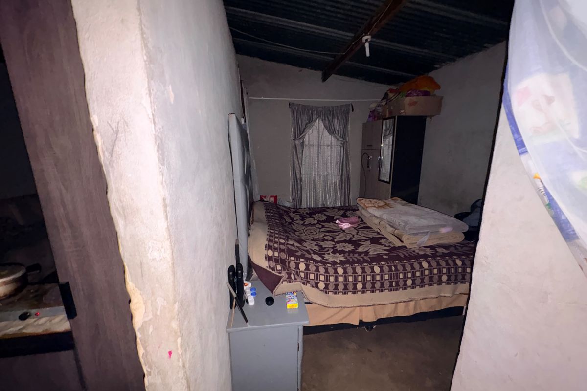 A basic bedroom featuring exposed roof rafters and unfinished wall surfaces, providing a functional sleeping space with potential for cosmetic improvement.