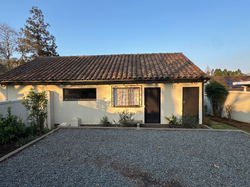 Rear view of a cottage featuring a terracotta tiled roof, security-fitted doors and windows, and a gravel courtyard area.