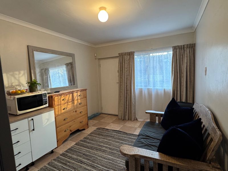 A functional living area featuring tiled flooring, neutral walls, and direct access to the exterior via a side door.