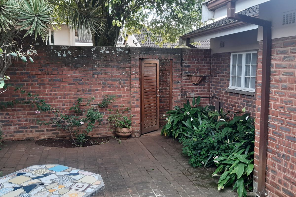 A private rear courtyard featuring brick boundary walls, paved flooring, and a timber access gate, providing a secluded outdoor space.