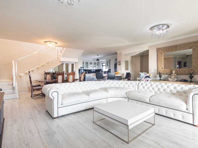 Spacious open-plan living area featuring a modern staircase, light laminate flooring, and a seamless transition into the kitchen space.