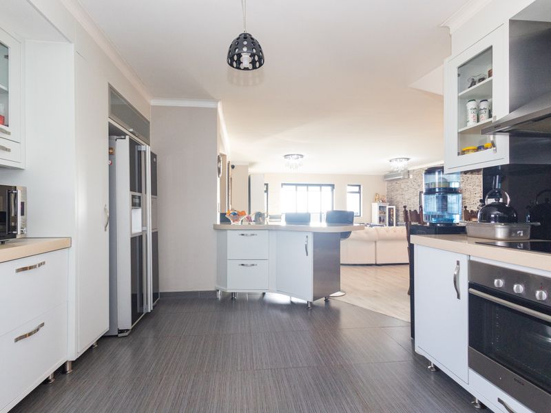 Spacious open-plan kitchen featuring modern white cabinetry, integrated appliances, and a central island, flowing seamlessly into the adjacent living area.
